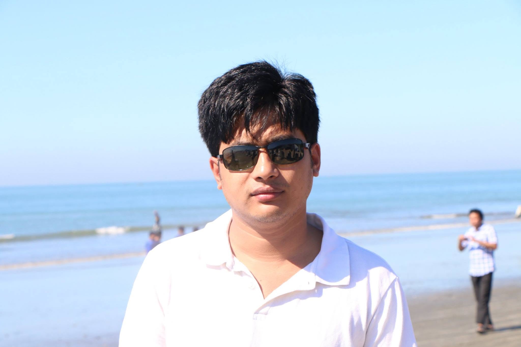 Mehedi Hasan in sunglasses and a white shirt by the sea